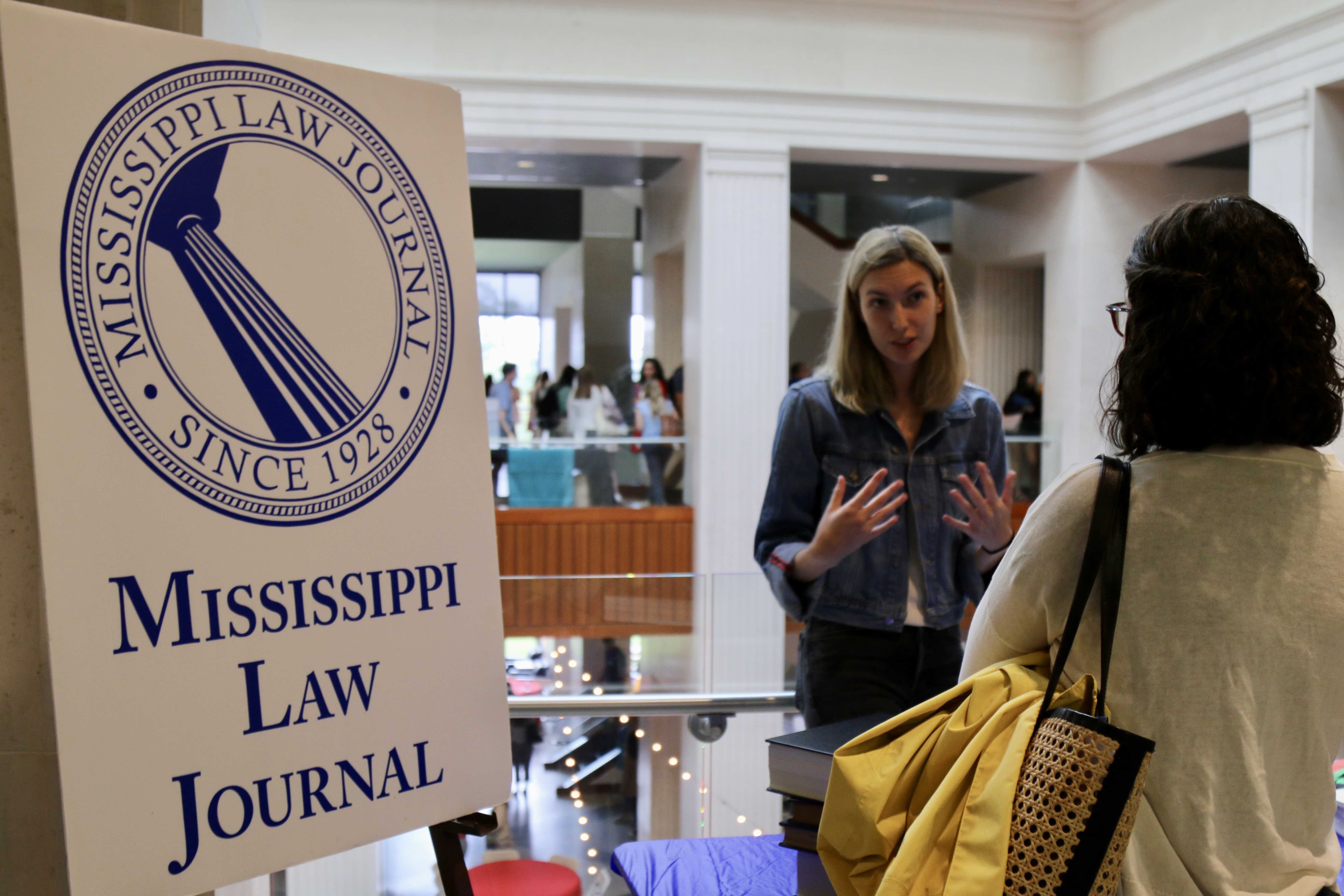 student speaking next to law journal sign 